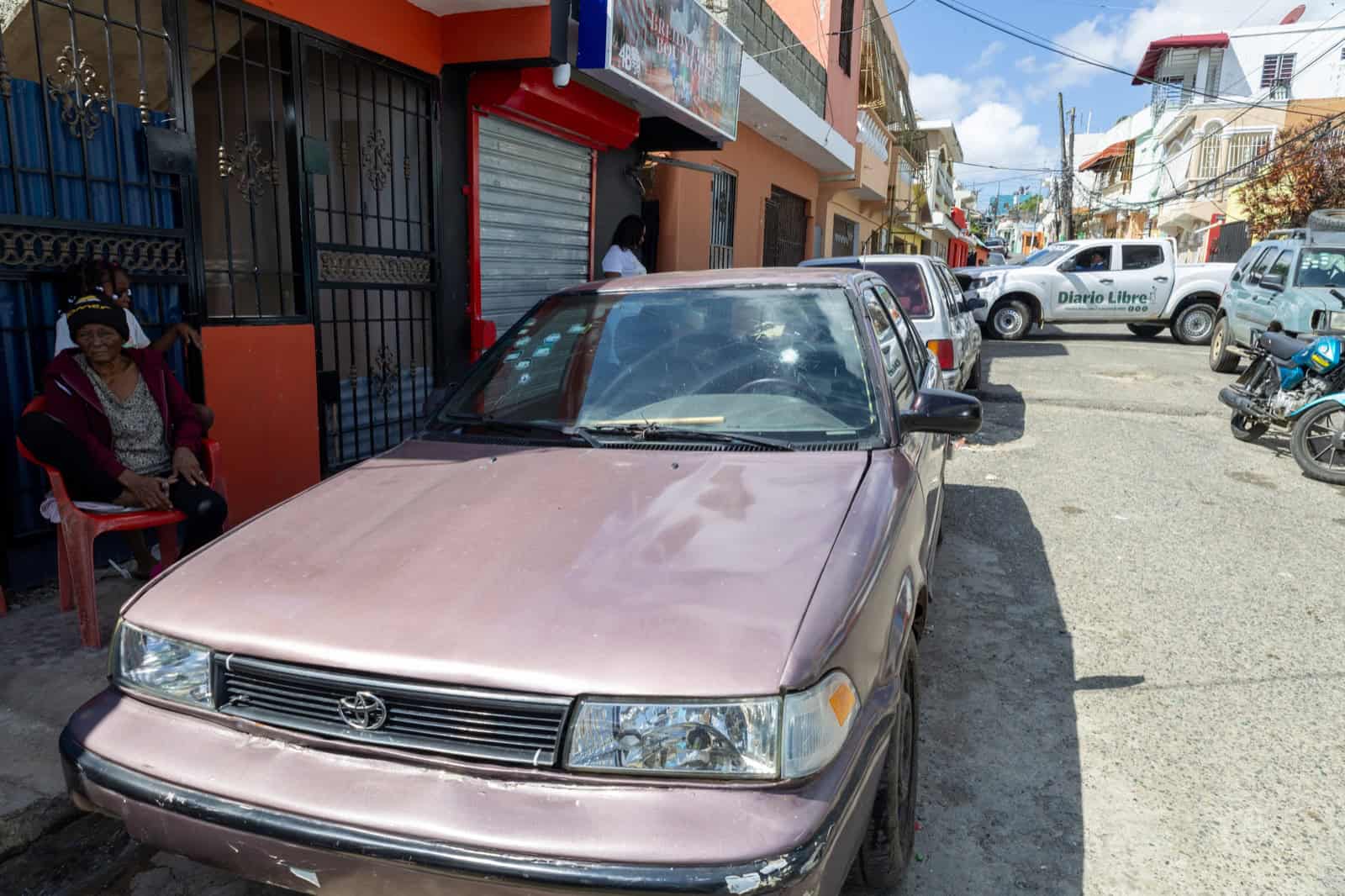 Un Toyota estacionado muestra el daño de los disparos en su cristal delantero tras la balacera.